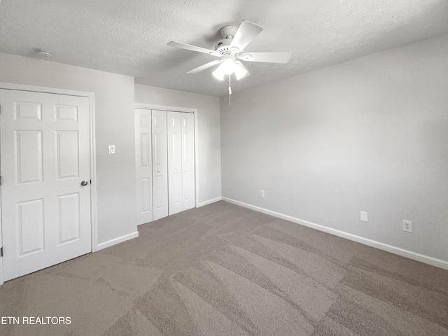 unfurnished bedroom with a textured ceiling, a ceiling fan, baseboards, a closet, and carpet