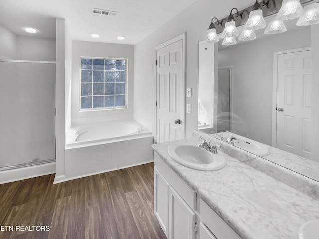 full bath with a stall shower, visible vents, wood finished floors, vanity, and a bath