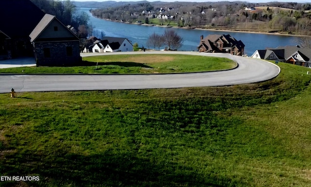 view of property's community with a water view and a lawn