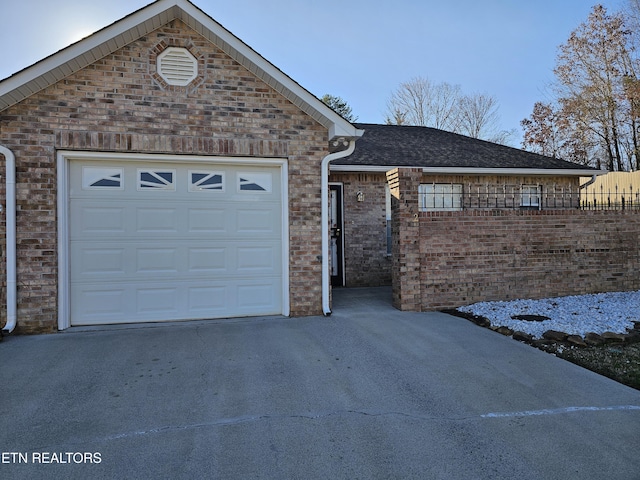 ranch-style home featuring driveway, brick siding, and a shingled roof