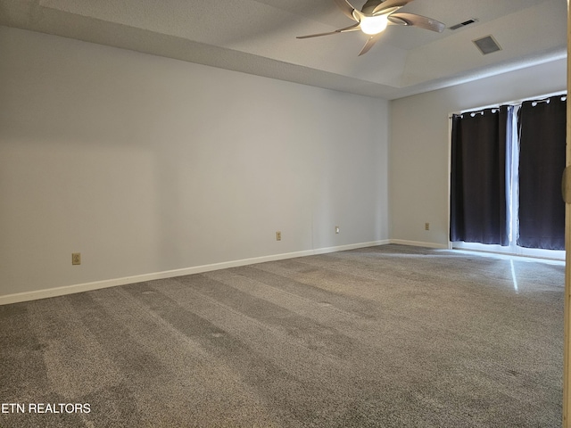 carpeted empty room featuring a ceiling fan, a tray ceiling, visible vents, and baseboards