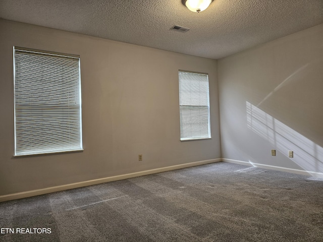 carpeted empty room featuring visible vents, a textured ceiling, and baseboards