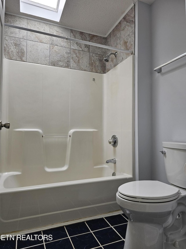 bathroom with a textured ceiling, toilet, a skylight, shower / bathing tub combination, and tile patterned floors