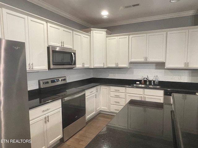 kitchen featuring visible vents, crown molding, dark wood-type flooring, appliances with stainless steel finishes, and a sink