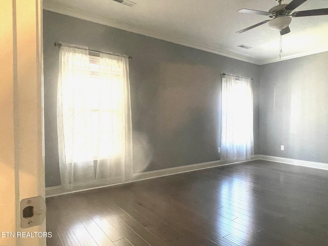 empty room featuring a healthy amount of sunlight, crown molding, and dark wood-style flooring