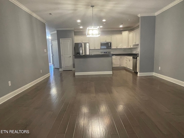 kitchen with dark countertops, baseboards, dark wood finished floors, appliances with stainless steel finishes, and white cabinetry