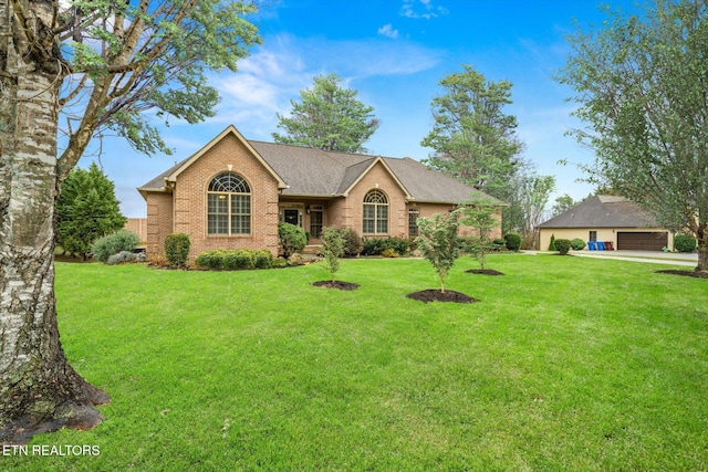 ranch-style house featuring brick siding, roof with shingles, a front yard, and a detached garage