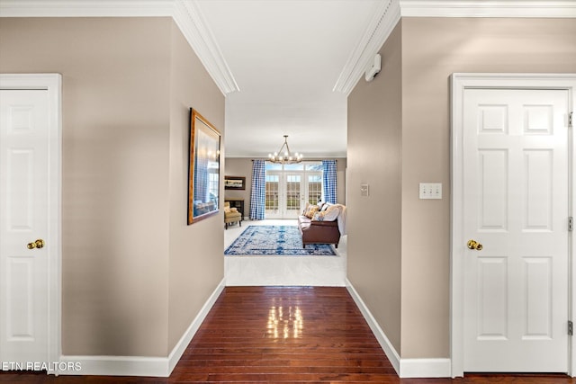 hallway featuring a notable chandelier, baseboards, crown molding, and wood finished floors