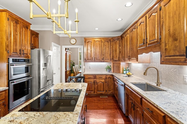 kitchen featuring decorative backsplash, light stone counters, stainless steel appliances, crown molding, and a sink