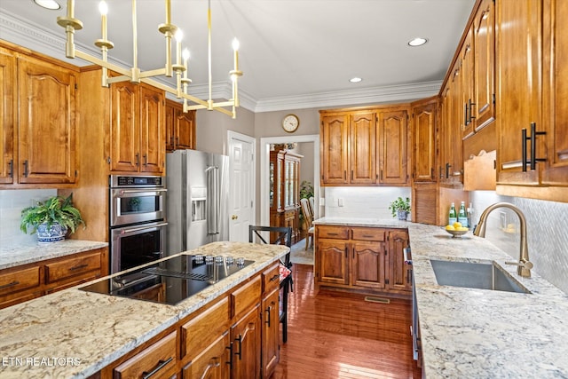 kitchen featuring dark wood-style floors, stainless steel appliances, brown cabinetry, a sink, and light stone countertops