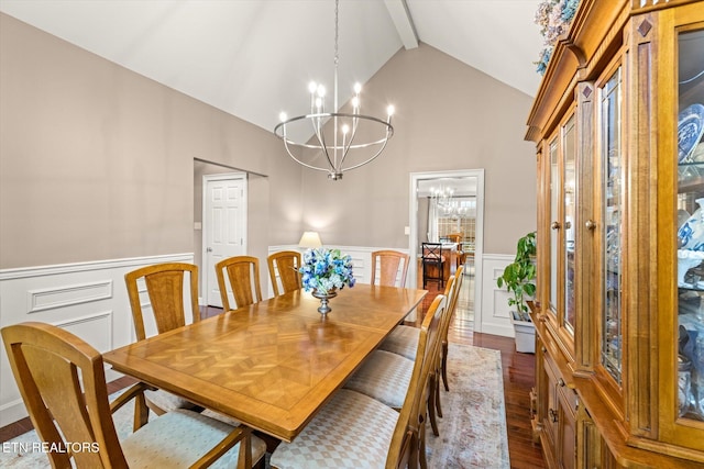 dining space featuring lofted ceiling with beams, an inviting chandelier, dark wood-style floors, and wainscoting