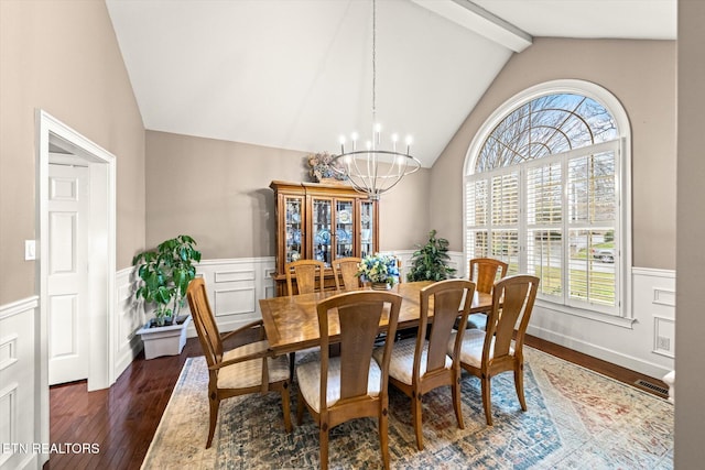 dining room with vaulted ceiling with beams, wood finished floors, a wealth of natural light, and an inviting chandelier