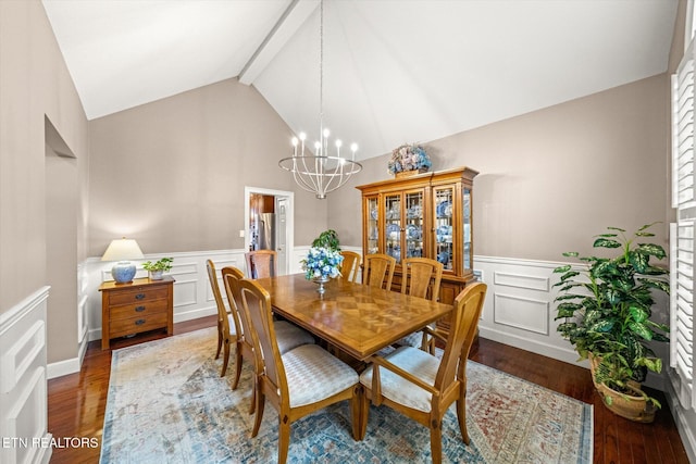 dining room with lofted ceiling with beams, wainscoting, wood finished floors, and a notable chandelier