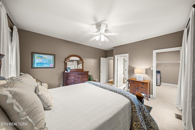 carpeted bedroom featuring visible vents, baseboards, ceiling fan, a walk in closet, and a closet