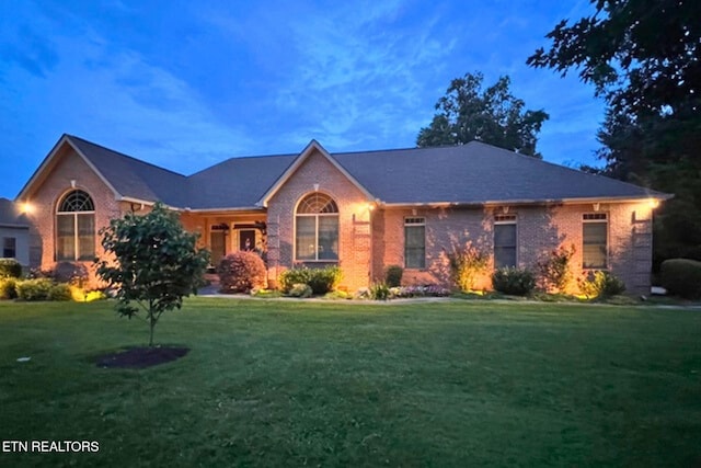 single story home with brick siding and a front yard