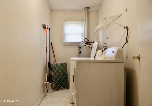 clothes washing area with laundry area, baseboards, washing machine and clothes dryer, and light tile patterned floors