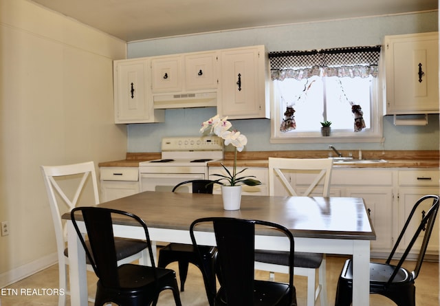 kitchen featuring under cabinet range hood, a sink, baseboards, white cabinets, and white range with electric cooktop