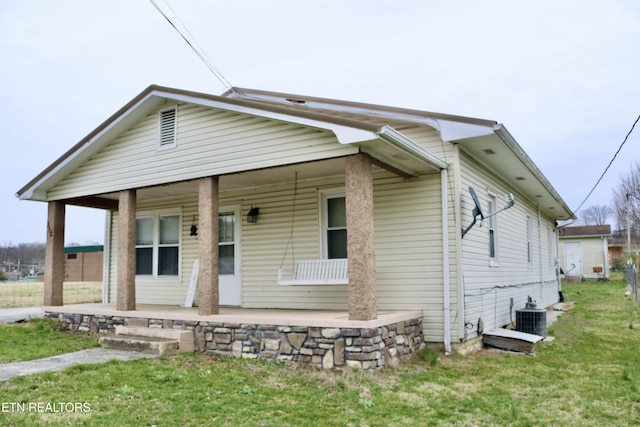 bungalow-style house featuring covered porch, central AC unit, and a front lawn