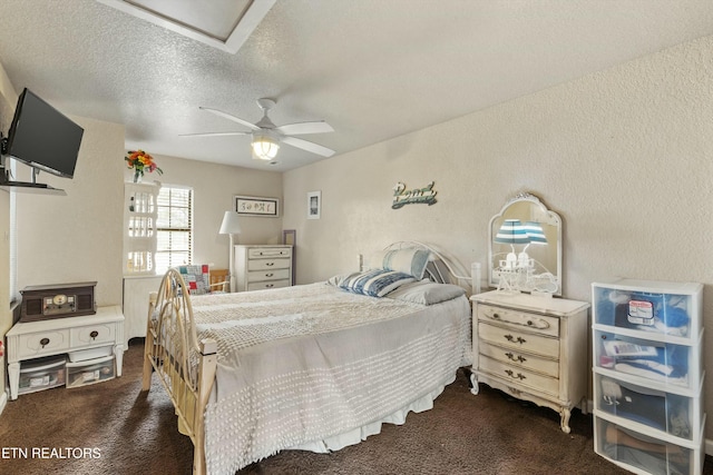 bedroom featuring a ceiling fan, carpet flooring, a textured wall, and a textured ceiling