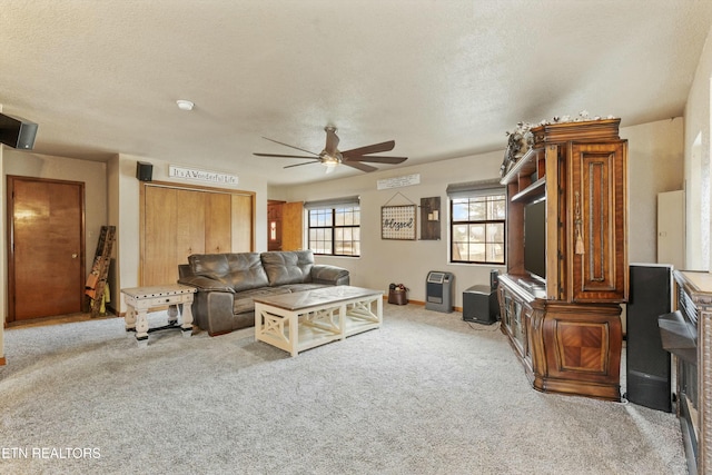 living area with a textured ceiling, a ceiling fan, and light colored carpet