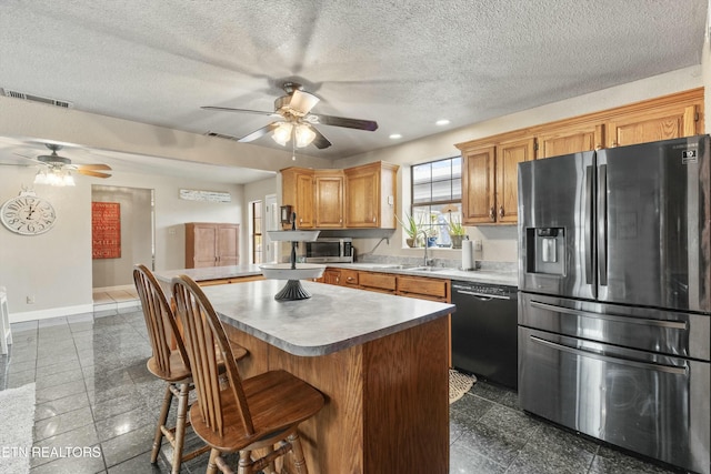 kitchen featuring a sink, a kitchen island, visible vents, baseboards, and appliances with stainless steel finishes