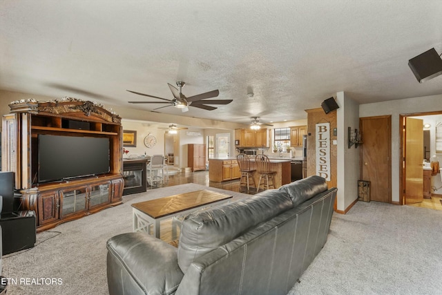 living room featuring light carpet, ceiling fan, baseboards, and a textured ceiling