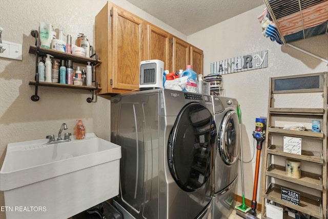 laundry room with cabinet space, a sink, washer and clothes dryer, and a textured ceiling