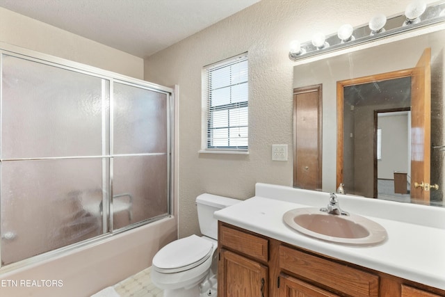 bathroom with toilet, shower / bath combination with glass door, a textured wall, and vanity