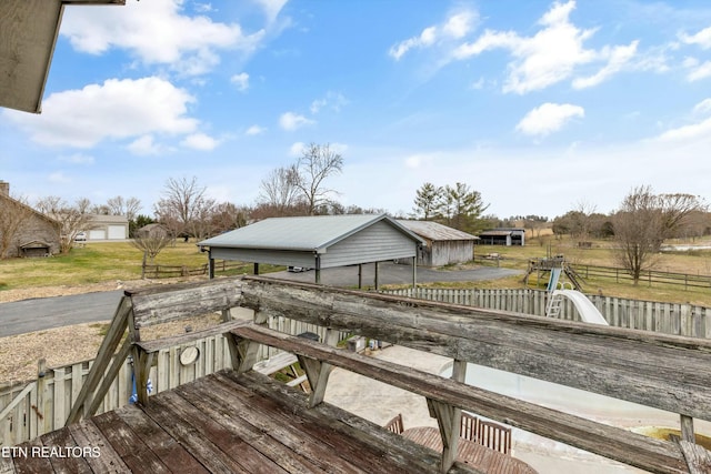 wooden terrace featuring an outdoor structure and fence