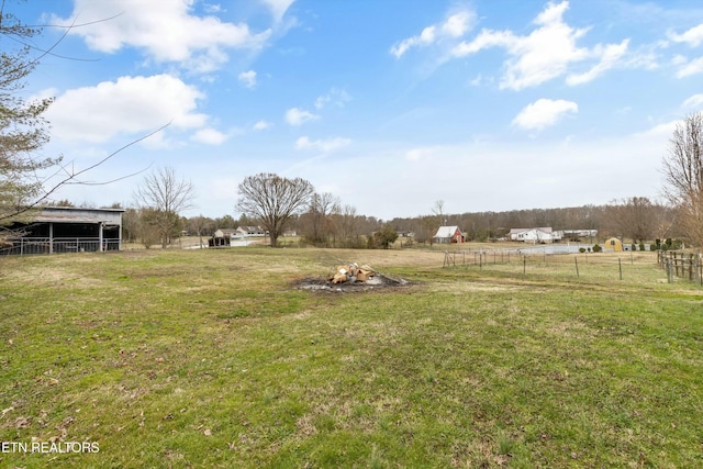 view of yard featuring fence, an outdoor structure, and a rural view