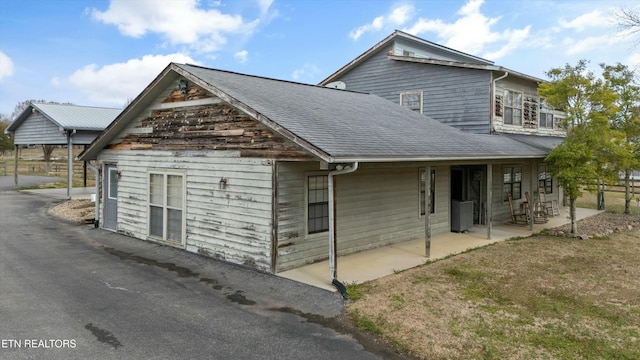 view of home's exterior featuring a patio and a shingled roof