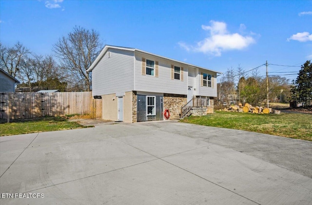 view of front facade with stairs, a front yard, fence, and driveway