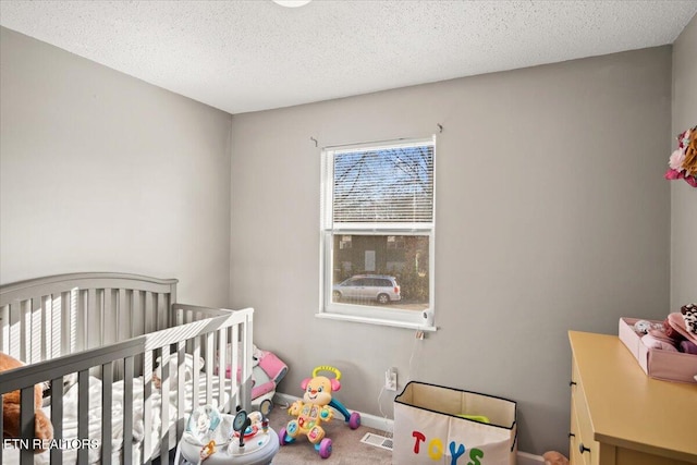 carpeted bedroom featuring a crib, visible vents, baseboards, and a textured ceiling