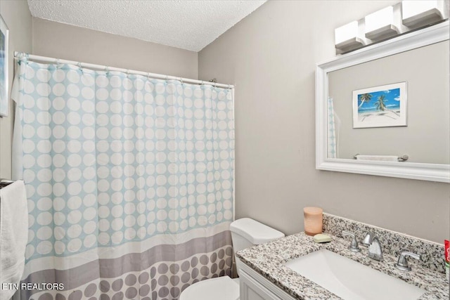 bathroom with vanity, curtained shower, toilet, and a textured ceiling