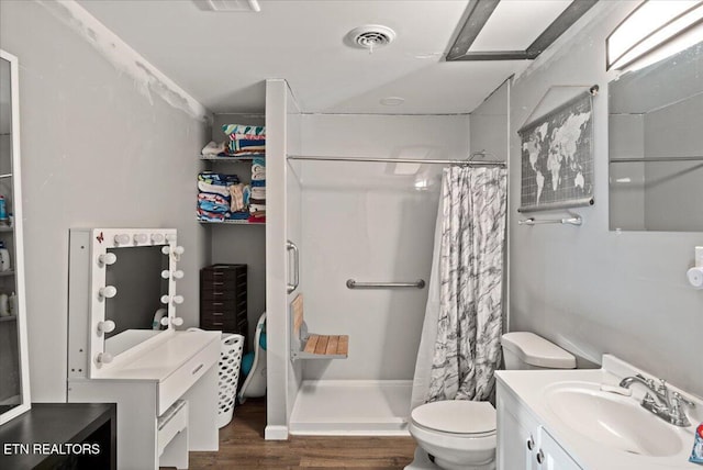 full bathroom with visible vents, toilet, wood finished floors, a shower stall, and vanity