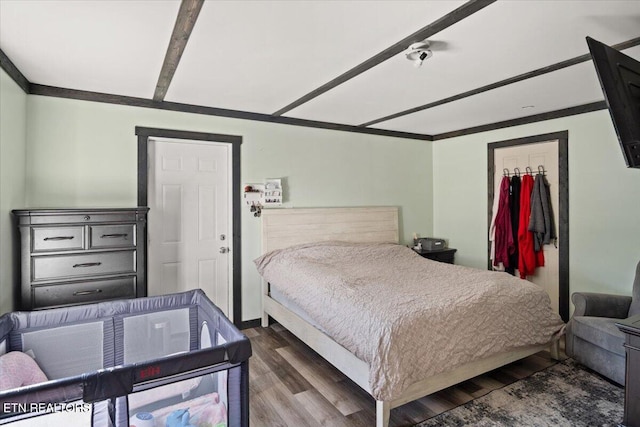 bedroom with a walk in closet, a closet, wood finished floors, and crown molding
