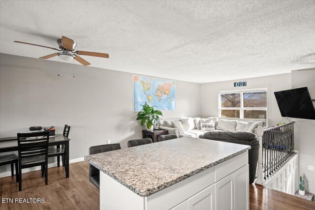 kitchen featuring open floor plan, a textured ceiling, dark wood finished floors, and white cabinets