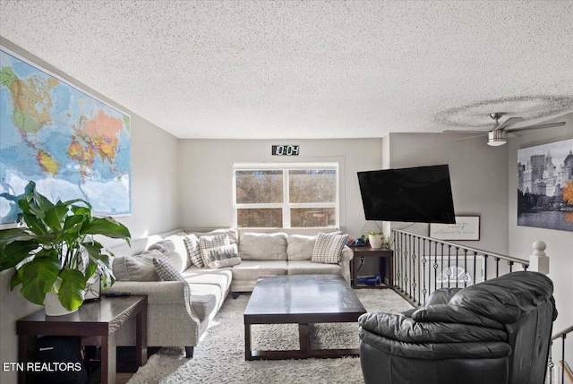 living room with carpet, ceiling fan, and a textured ceiling