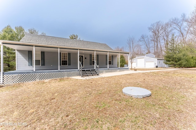 view of front of property with a porch, a shingled roof, a garage, an outdoor structure, and a front lawn