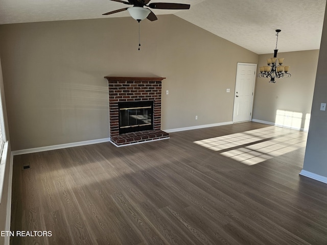 unfurnished living room with lofted ceiling, ceiling fan with notable chandelier, a fireplace, baseboards, and dark wood-style floors