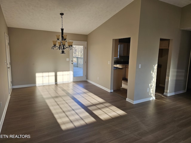 unfurnished dining area featuring dark wood-style flooring, a notable chandelier, a textured ceiling, and baseboards