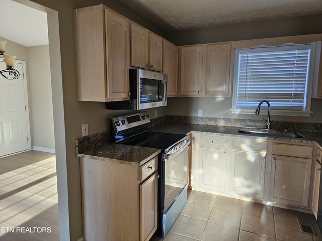 kitchen with light tile patterned floors, visible vents, appliances with stainless steel finishes, a sink, and dark stone countertops