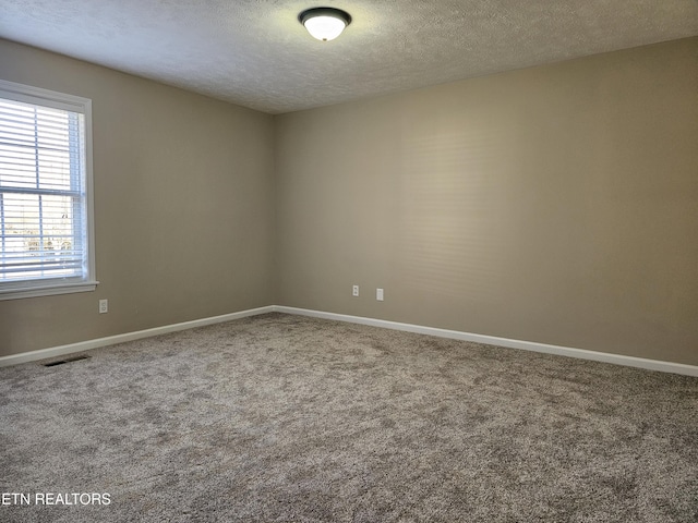 carpeted empty room featuring visible vents, a textured ceiling, and baseboards