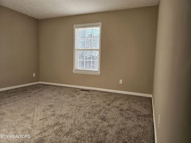 carpeted empty room with visible vents, a textured ceiling, and baseboards