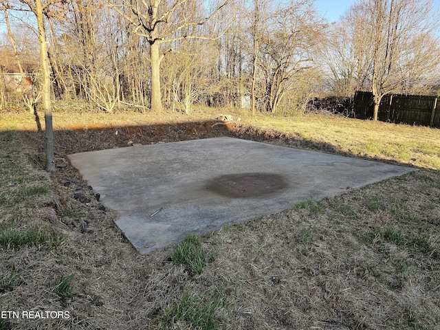 view of yard with a patio, fence, and driveway