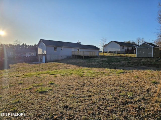 view of yard featuring a storage shed, an outbuilding, fence, and a wooden deck