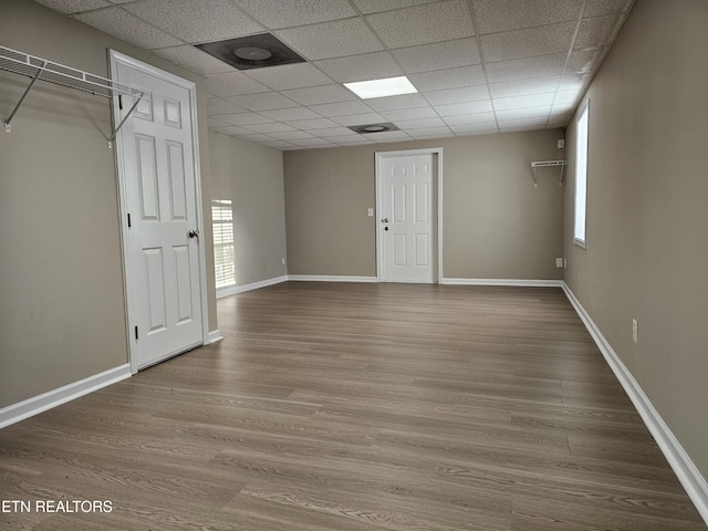 unfurnished room featuring wood finished floors, a paneled ceiling, and baseboards