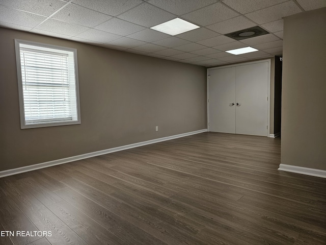 unfurnished room with a paneled ceiling, baseboards, and dark wood finished floors