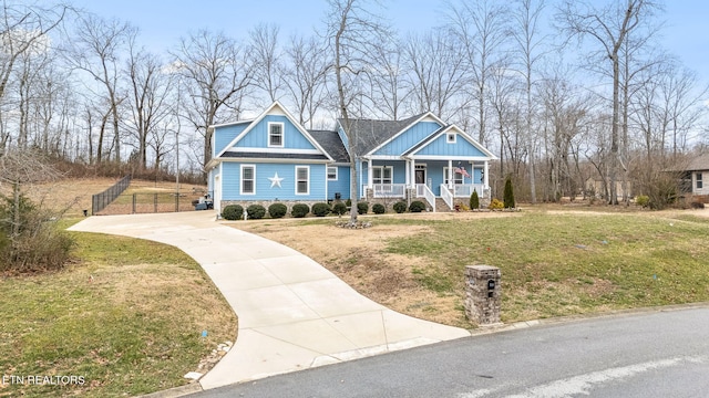 craftsman-style house with a porch, concrete driveway, board and batten siding, and a front lawn