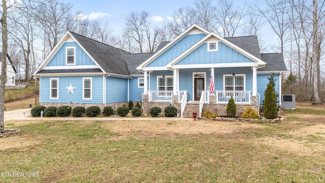 craftsman inspired home with a shingled roof, a front lawn, a porch, and board and batten siding